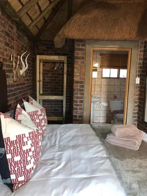 a bedroom with a bed and a brick wall at Vilagama Game Lodge in Naboomspruit