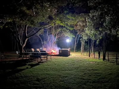 a fire in a park at night with chairs and trees at Vilagama Game Lodge in Naboomspruit
