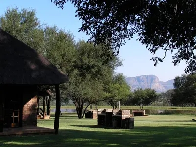 a pavilion with trash cans in a park with mountains at Vilagama Game Lodge in Naboomspruit