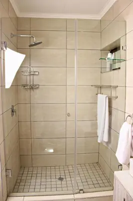 a shower with a glass door in a bathroom at Zoe Bush Lodge in Pretoria