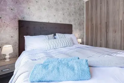 a white bed with two blue towels on it at Alimama Spaces: The Manson's Blyde in Pretoria