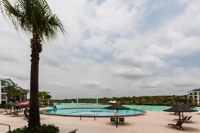 a pool with a palm tree and tables and umbrellas at Alimama Spaces: The Manson's Blyde in Pretoria