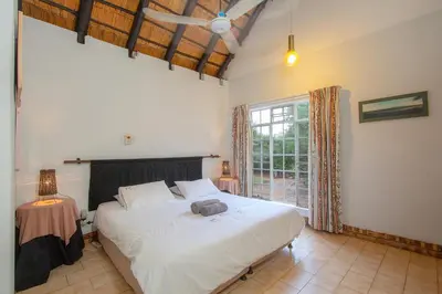 a bedroom with a large white bed and a window at NJIRI - Your part of Africa in Marloth Park