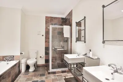 a bathroom with a toilet and a sink and a shower at The Wild Olive Guest House in Centurion