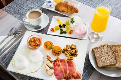 a breakfast table with a plate of breakfast foods and a cup of coffee at The Wild Olive Guest House in Centurion