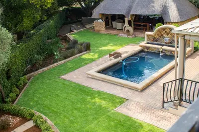a backyard with a swimming pool in the grass at The Wild Olive Guest House in Centurion