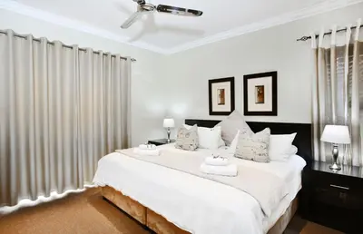 a white bedroom with a large bed with white pillows at The Wild Olive Guest House in Centurion