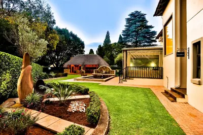 a garden with a house and a yard with grass and a yard at The Wild Olive Guest House in Centurion