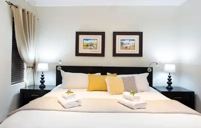 a bedroom with a large bed with towels on it at The Wild Olive Guest House in Centurion