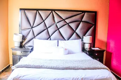 a bedroom with a large white bed with two night stands at Thavhani Guest House in Thohoyandou