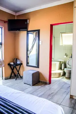 a room with a bed and a bathroom with a toilet at Thavhani Guest House in Thohoyandou