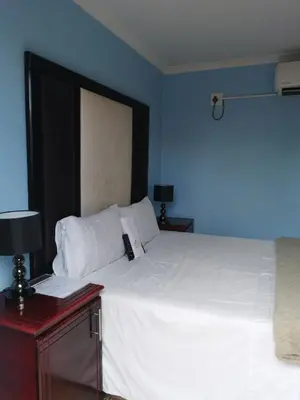 a bedroom with a large white bed with a blue wall at Thavhani Guest House in Thohoyandou