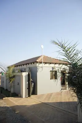 a white house with a garage and a palm tree at Thavhani Guest House in Thohoyandou