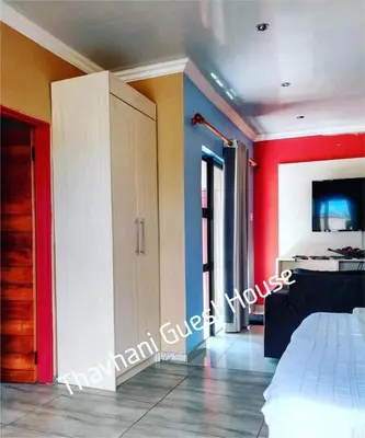 a bedroom with a white bed and a red wall at Thavhani Guest House in Thohoyandou