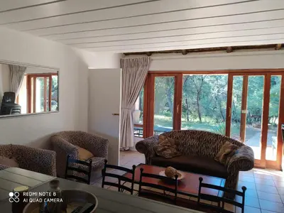 a living room with a couch and chairs and windows at Bush Dream, Mabalingwe in Mabula