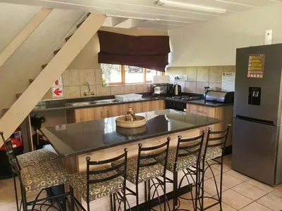 a kitchen with a sink and a counter with chairs at Bush Dream, Mabalingwe in Mabula