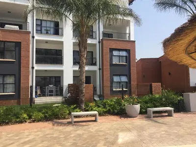 two benches in front of a building with palm trees at The Blyde - Beachfront in Pretoria
