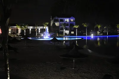 a swimming pool with a fountain at night at The Blyde - Beachfront in Pretoria