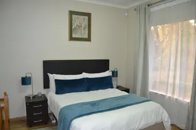 a bedroom with a bed with blue pillows and a window at Green Grove Villa in Centurion