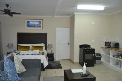 a bedroom with a bed and a couch and a table at Green Grove Villa in Centurion