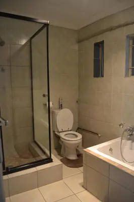a bathroom with a toilet and a shower and a sink at Green Grove Villa in Centurion