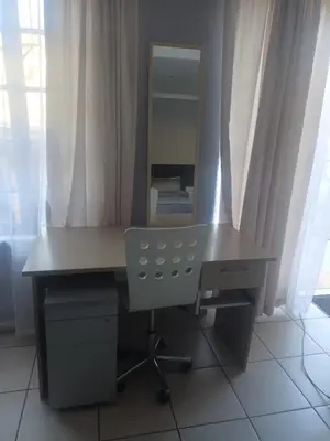 a desk with a mirror and a chair in a room at Home Sweet Home in Polokwane