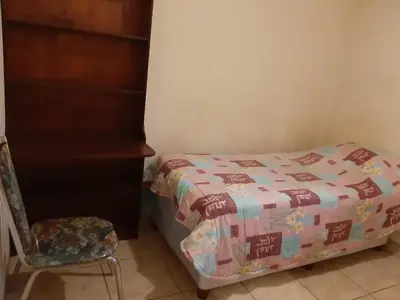 a small bedroom with a bed and a chair at Roullas gardens in Pretoria