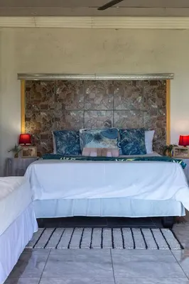 a large bed in a room with a stone wall at Hornbills lodge bnb in Mbabat