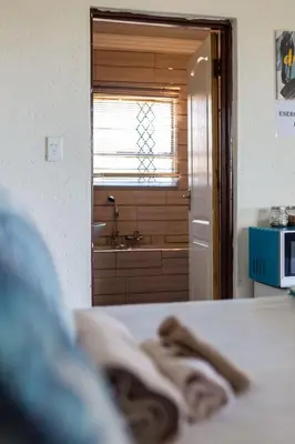 a room with a bathroom with a sink and a bed at Hornbills lodge bnb in Mbabat