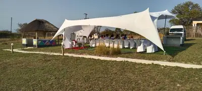 a group of people standing under a white tent at Hornbills lodge bnb in Mbabat