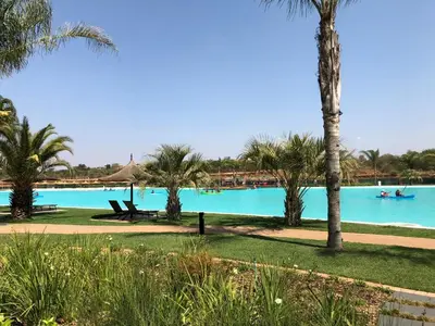 a large pool with palm trees and people in a boat at The Blyde Riverwalk Estate in Pretoria