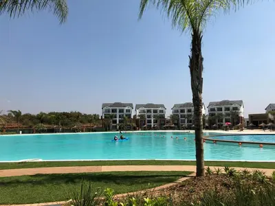 a large swimming pool with a palm tree and condos at The Blyde Riverwalk Estate in Pretoria