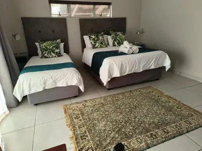 a bedroom with two beds and a rug at Big Tree Guesthouse Brits in Brits