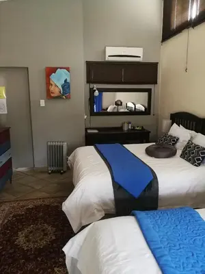a hotel room with two beds and a mirror at Big Tree Guesthouse Brits in Brits
