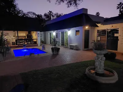 a house with a pool in the yard at night at Big Tree Guesthouse Brits in Brits