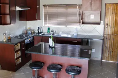 a kitchen with a sink and a stove and stools at Rip van Winkel Guest House in Lephalale
