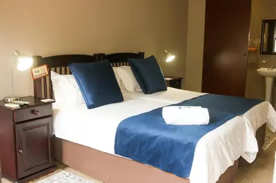 a bedroom with a large bed with blue pillows at Rip van Winkel Guest House in Lephalale