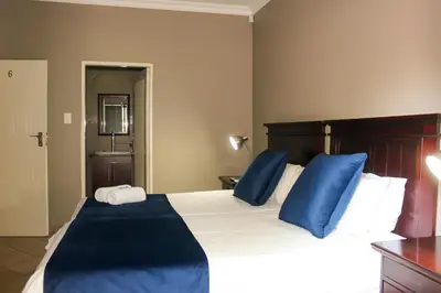 a bedroom with a large bed with blue pillows at Rip van Winkel Guest House in Lephalale
