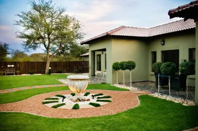 a fountain in a yard in front of a house at Rip van Winkel Guest House in Lephalale