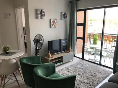 a living room with a television and chairs and a table at The Blyde River Walk Estate in Pretoria