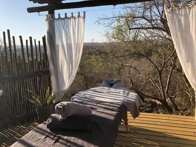 a bed sitting on a deck with a view of the mountains at The Wild Blue Lodge SAFARI & SPA in Hoedspruit