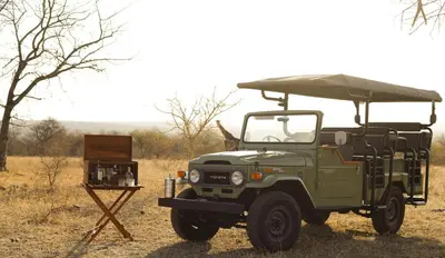 a green military jeep parked in a field at The Wild Blue Lodge SAFARI & SPA in Hoedspruit