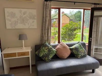 a couch with pillows in a living room with a window at Thyme Inn on Greenway in White River