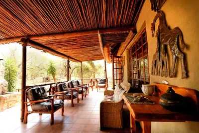 a living room with couches and a table and chairs at Lovely holiday home bordering Kruger National Park in Marloth Park