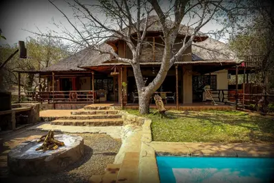 a house with a tree in front of it at Lovely holiday home bordering Kruger National Park in Marloth Park