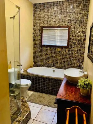a bathroom with a tub and a toilet and a sink at Douglas Villas in Tzaneen