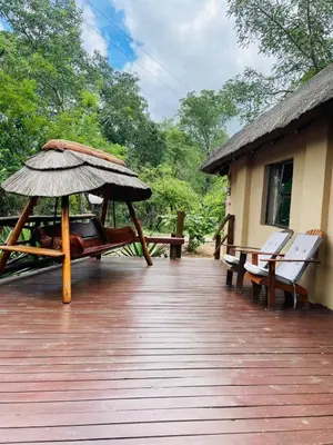 a deck with benches and an umbrella on a house at Pan African Lodge & Safari in Marloth Park