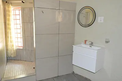 a white bathroom with a sink and a mirror at Pan African Lodge & Safari in Marloth Park