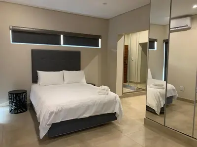 a bedroom with a large white bed and a mirror at 77 On Burger in Polokwane