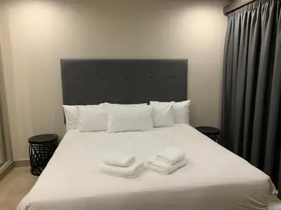 a white bed with three towels on it at 77 On Burger in Polokwane